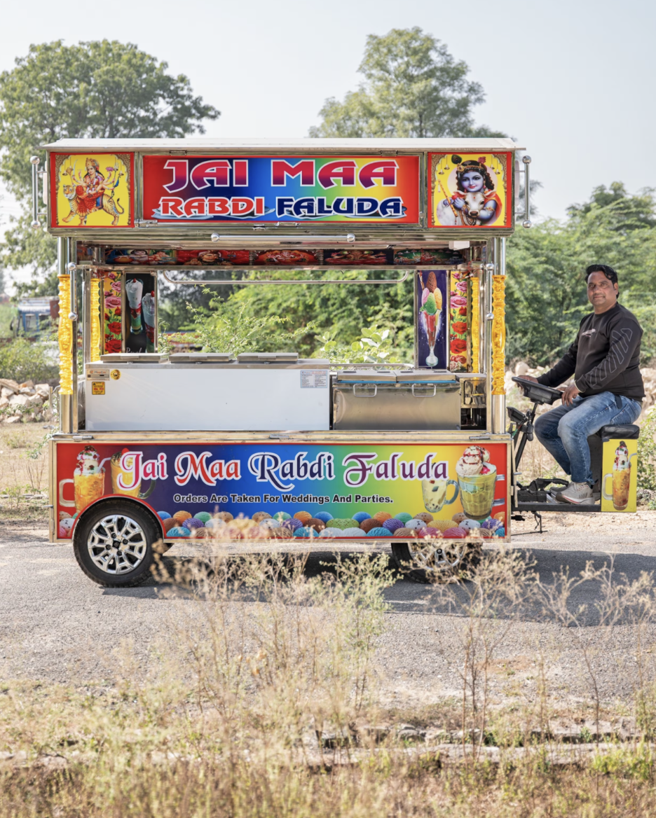 В 2013 году Говардхан Лал Мали оставил сельское хозяйство и начал делать мороженое. Точнее — морозильные фургоны. Он превратил обычные индийские мини-грузовички, которые здесь называют темпо, в яркие тележки с морозильниками, подсветкой и колонками. Каждый такой «мороженомобиль» он собирает за 150 000 рупий (примерно $1750). Его мастерская выпускает около сотни таких фургонов в год — и спрос только растёт. Сейчас Мали — не просто мастер. Он — часть целой индустрии, которая превратила Гангапур в неформальную столицу мороженого Индии.