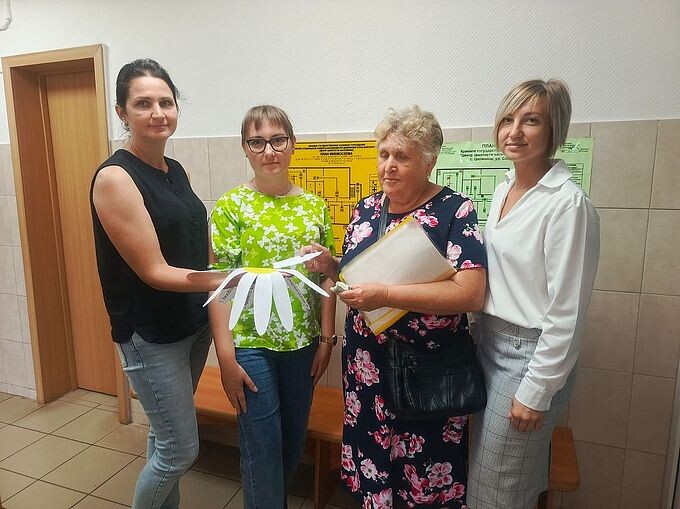 Женщины держат в руках символ праздника — бумажную ромашку