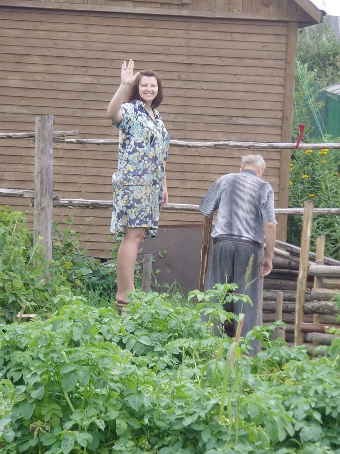 Дедушка учит Олю И. вкапывать брёвна для будущего забора. Оля И. в восторге.