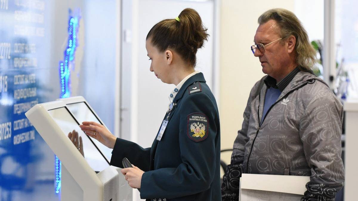    Сотрудница ФНС помогает посетителю со сдачей налоговой отчетности / Фото: Сергей Пятаков / РИА Новости