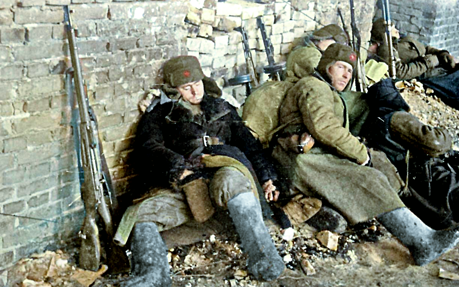 Уставшие солдаты отдыхают под защитой стены.  Сталинград, начало 1943 г.