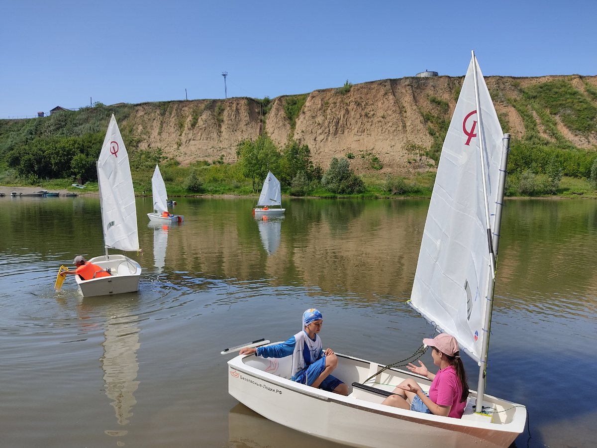 Корреспондент Юлия Непомнящих берет интервью у .юной яхтсменки. Процесс происходит у берега, поэтому его участницы без спасательных жилетов)