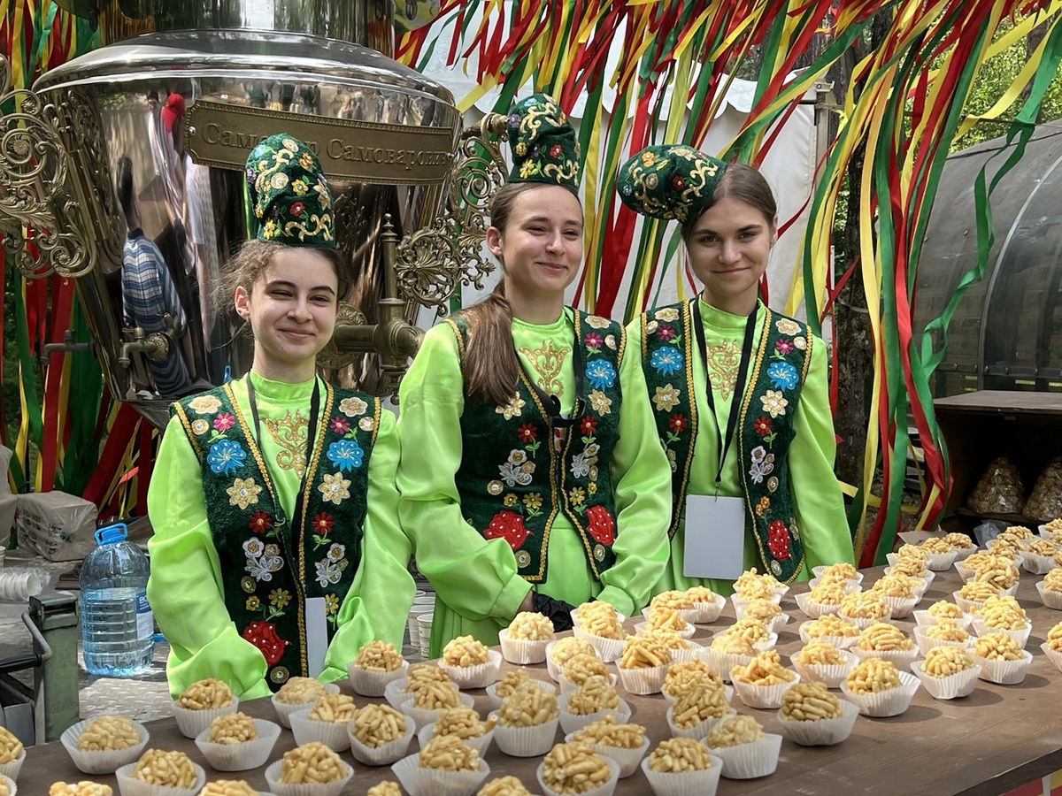 За красивыми девушками стоит гигантский самовар, из которого гостей угощают душистым чаем