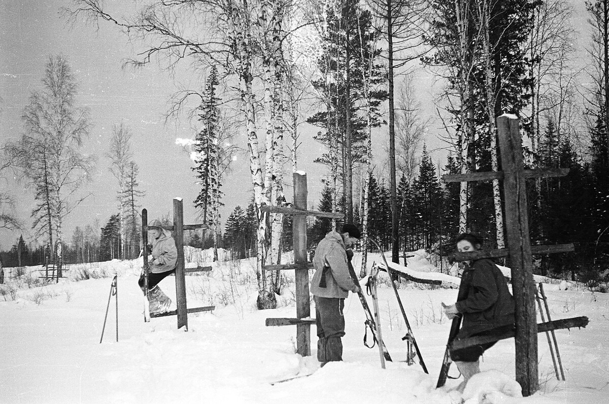 Кадр 6_28 с Фотопленки 6 из архива Иванова. Люда Дубинина, Семен Золотарев и Зина Колмогорова чистят лыжи от снега с помощью ножиков у каких-то странных столбов.