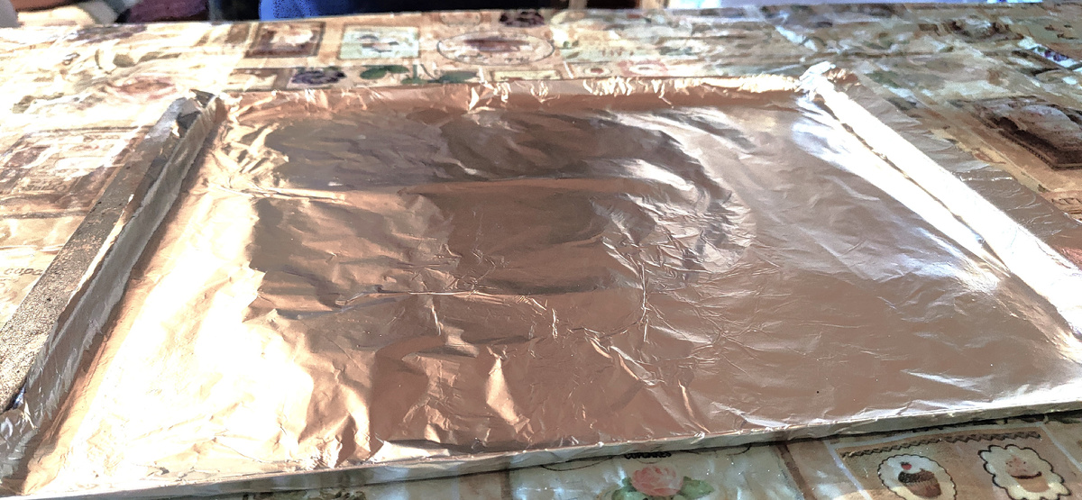 Противень для шанежек покрыт фольгой и смазан растительным маслом