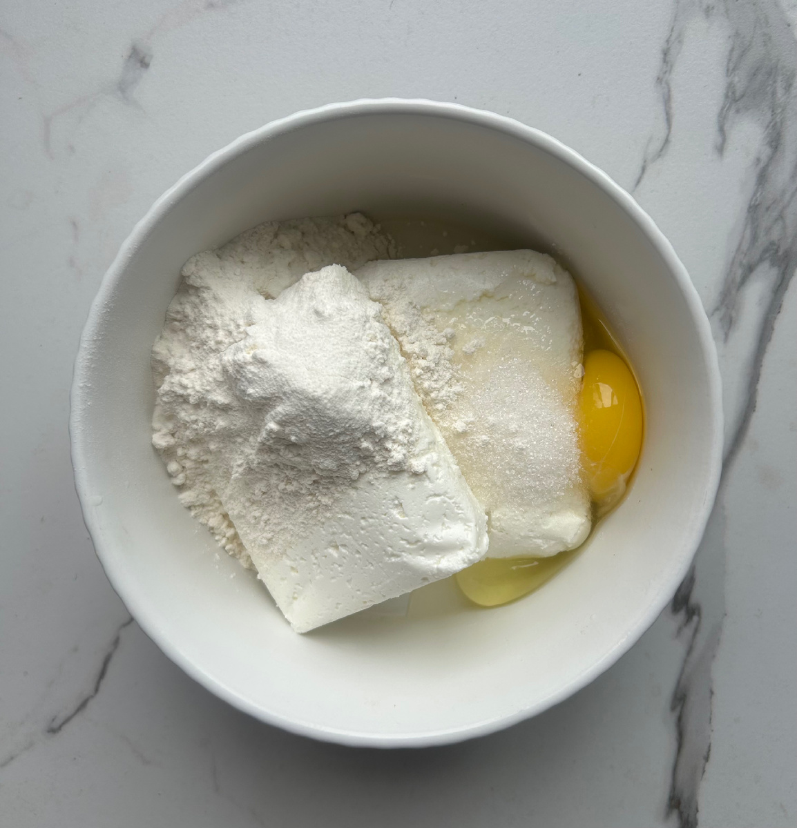 Творог,яйцо,муку,разрыхлитель и сахар тщательно перемешать. Получившееся тесто разделить на 4 равные части и сформировать шарики. Выложить на противень,застеленный фольгой и сформировать ватрушки. Дном стакана я сформировала углубление для начинки.