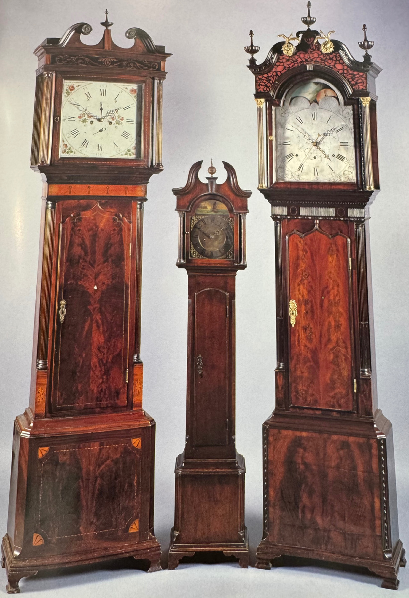 Трое напольных часов XVIII в., одни из них миниатюрной формы. В это время появляется белый эмалевый циферблат, а с ним приходит искусство его росписи. Однако хорошее качество рисунка встречалось столь же редко, как и достойное качество металлической пазухи свода. Часы справа украшены полуаркой, представляющей различные фазы луны. На полуарке миниатюрных напольных часов изображен морской пейзаж, который мог двигаться вверх-вниз, развлекая зрителей. Плохой вкус незаметно прокладывал себе дорогу даже в годы правления Георга III. Позолоченные детали, которыми декорирован фронтон часов, находящихся справа, уменьшают достоинства дизайна, а пестрота верхней части заставила бы мебельщиков просто содрогнуться. Яркий шпон использован настолько некомпетентно, что полностью исключается "зеркальный" эффект, имевшийся в лучших образцах метода деления на четыре части (размещение бок о бок идентичных пластинок шпона)