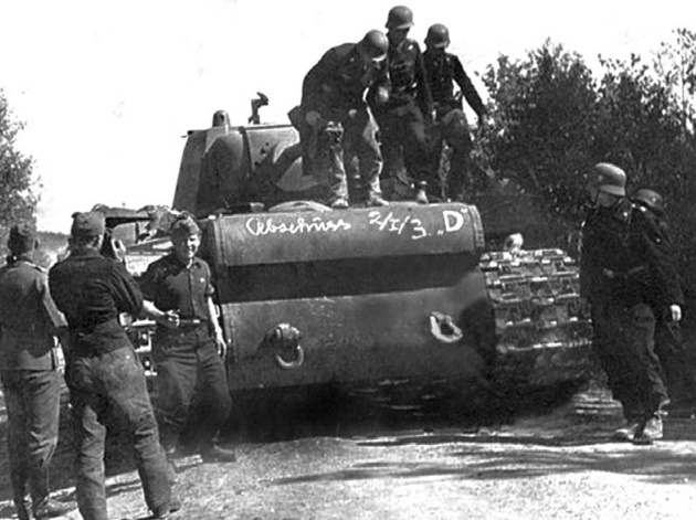 Немецкие военнослужащие осматривают «расейняйский КВ», 25 июня 1941 года. Как указывает М. В. Коломиец, надпись на корпусе танка свидетельствует о том, что он был уничтожен расчётом орудия D 2-й батареи 1-го дивизиона 3-го зенитного полка