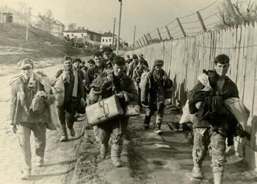 Колонна депортируемых гражданских лиц на ул. III Интернационала (современная улица Калинина) в районе пересечения с улицей Красноармейской у Галерных сараев в Брянске. Предположительно 1942 год.