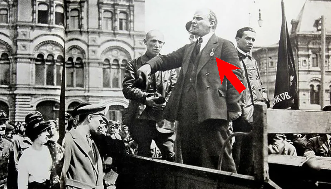 В. И. Ленин выступает, стоя на грузовике. На его груди висит непонятная медаль или значок