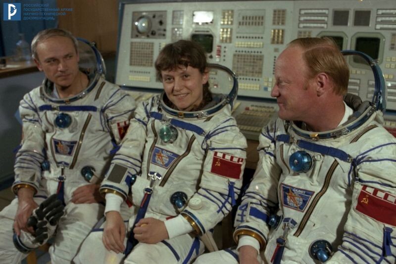 Экипаж корабля «Союз Т-12» – космонавты В.А. Джанибеков, С.Е. Савицкая и И.П. Волк (слева направо) у пульта инструкторов в зале тренажеров ЦПК им. Ю.А. Гагарина. Звездный городок, 1984 г. РГАНТД. Арх. № 0-4198 цв.
