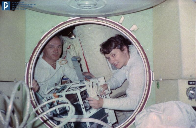 Командир В.А. Джанибеков и бортинженер С.Е. Савицкая готовят универсальный ручной инструмент (УРИ) перед выходом в открытый космос. 25 июля 1984 г. РГАНТД. Арх. № 1-3975 цв.
