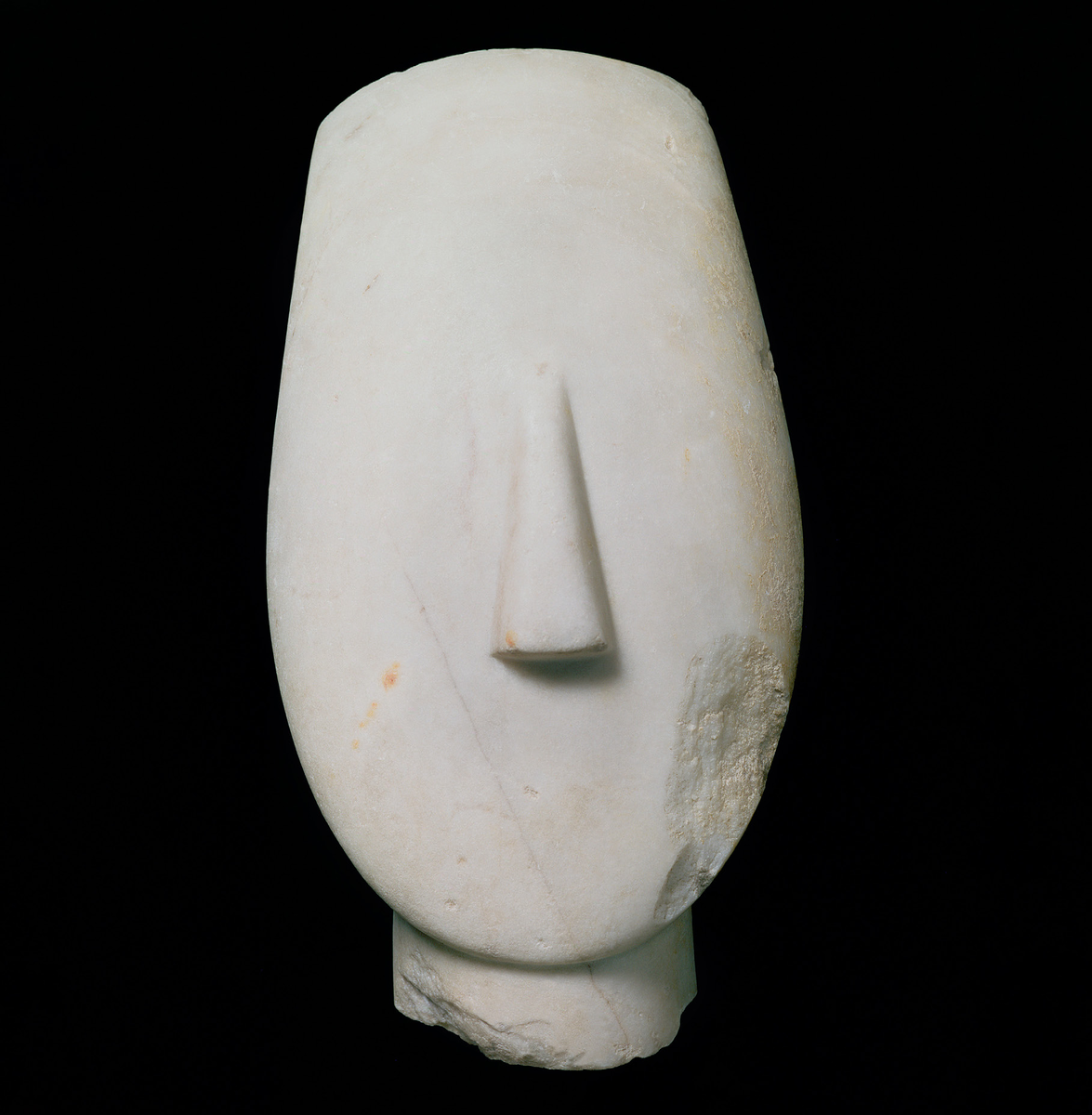 Керосинская голова (3-е тысячелетие до н. э.)
Эта мраморная голова, обнаруженная на острове Керос (Киклады), предположительно является частью статуи идола или женского божества, чья точная роль и личность неизвестны. Ее характерная U-образная форма, утонченный стиль и гладкая текстура мрамора позволяют отнести ее к раннему бронзовому веку (примерно 2700-2400 гг. до н.э.). Оригинальная статуя, вероятно, достигала почти полутора метров в высоту и изображала обнаженную женщину в статичной позе: руки скрещены на груди, ноги сомкнуты. Высота сохранившейся головки составляет около 25 сантиметров. Белый мрамор, скорее всего, был украшен или полностью покрыт краской.
Париж, музей du Louvre, Departement des Antiquités Grecques, Étrusques et Romaines.