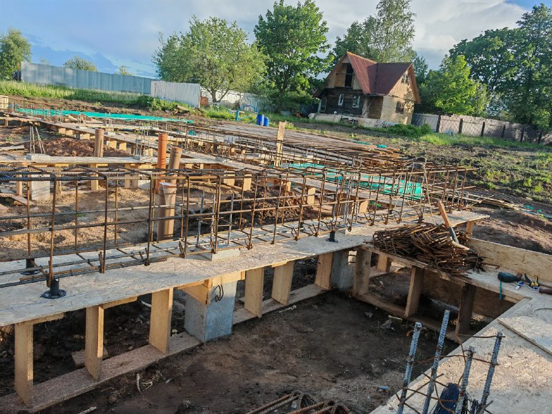 Подготовка к заливке: армопояс установлен в опалубку
Снизу видны сваи, на которые опирается ростверк. Такой подход дает фундаменту высокую несущую способность и устойчивость к подвижкам грунта.