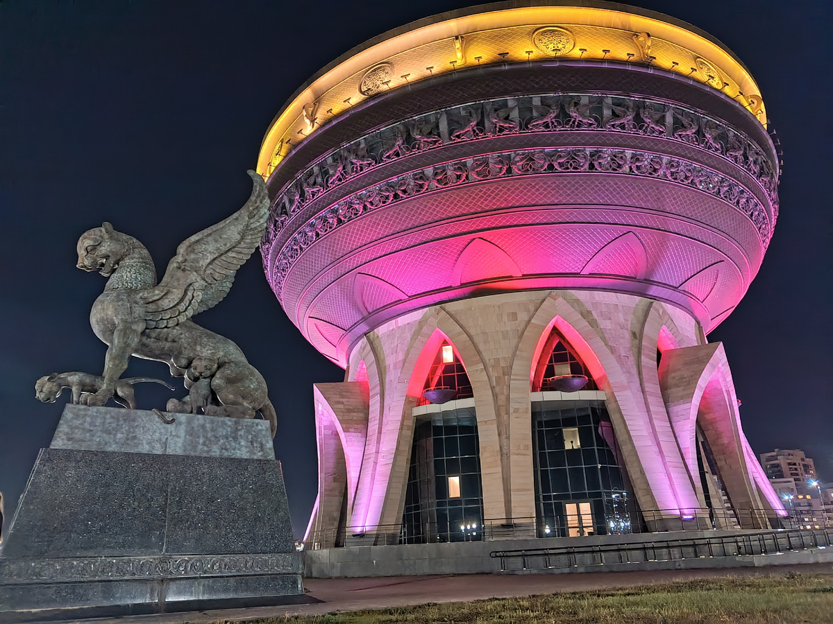 По периметру "Чашу" окружают крылатые символы Казани - Зиланты. Подсветка основания красным цветом вероятно символизирует горящий очаг.