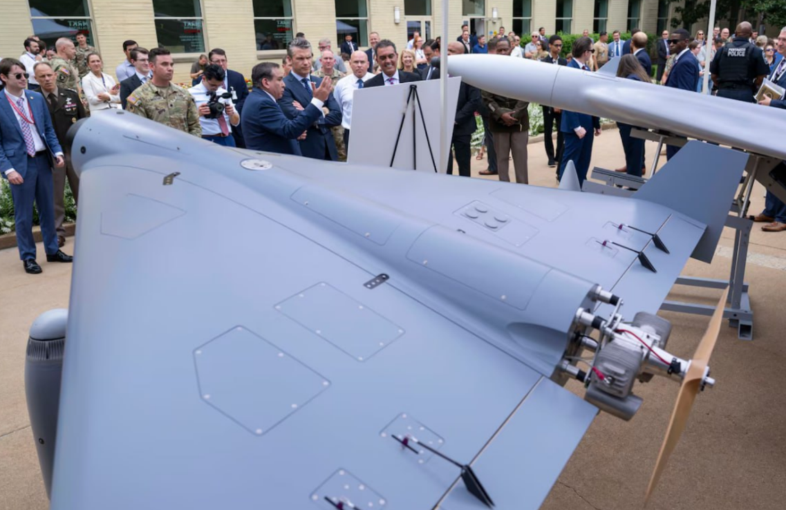 На фотографии: 16 июля 2025 года в США прошла выставка, посвящённая беспилотным летательным аппаратам (БПЛА), где публике и лично представителю Пентагона Питу Хегсету были представлены 18 моделей ударных дронов, поразительно напоминающих российскую «Герань-2» и иранский «Шахед-136». Источник фото: https://defence-industry.eu/wp-content/uploads/2025/07/Pentagon-to-accelerate-U.S.-production-of-low-cost-drones-for-battlefield-use.jpg