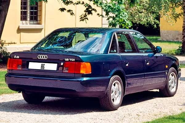Задняя часть этого автомобиля является логичным и гармоничным завершением его классического и основательного дизайна. Она так же, как и весь кузов, излучает надежность и сдержанность, без лишних элементов.Задние фонари обычно имеют горизонтальное расположение, что визуально расширяет автомобиль и придает ему более внушительный вид. Их форма лаконична и функциональна, обеспечивая хорошую видимость сигналов. В зависимости от версии, между фонарями могла быть расположена светоотражающая полоса или дополнительный элемент, объединяющий их в единый блок, что было характерной чертой дизайна Audi того периода.Крышка багажника имеет достаточно большую площадь и оптимальную высоту для удобной загрузки вещей. Она плотно прилегает к кузову, подчеркивая точность сборки.Задний бампер выглядит массивно и надежно, продолжая линию защиты всего автомобиля. Он гармонично вписывается в общий силуэт, не перегружая заднюю часть.Для версии универсал (Avant) задняя часть отличалась особенно большой и практичной дверью багажника, которая открывала доступ к огромному грузовому пространству. При этом дизайн универсала также сохранял общую строгость и элегантность.В целом, задняя часть этого автомобиля завершает образ добротной, продуманной и долговечной машины, которая выглядит солидно и уверенно на дороге.