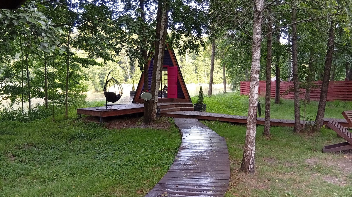 Фиолетовый домик в комплексе Di.Land, июль 2025. Вид от беседки на домик-шалаш. Фото из личного архива автора.