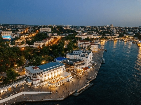 Вечерняя панорама центральной бухты Севастополя: набережная, огни города и море, которое принимает закат.