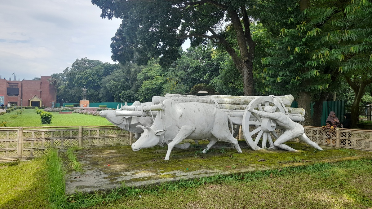 Скульптура на территории фонда народного творчества и ремёсел Бангладеш и здание музея, на заднем плане