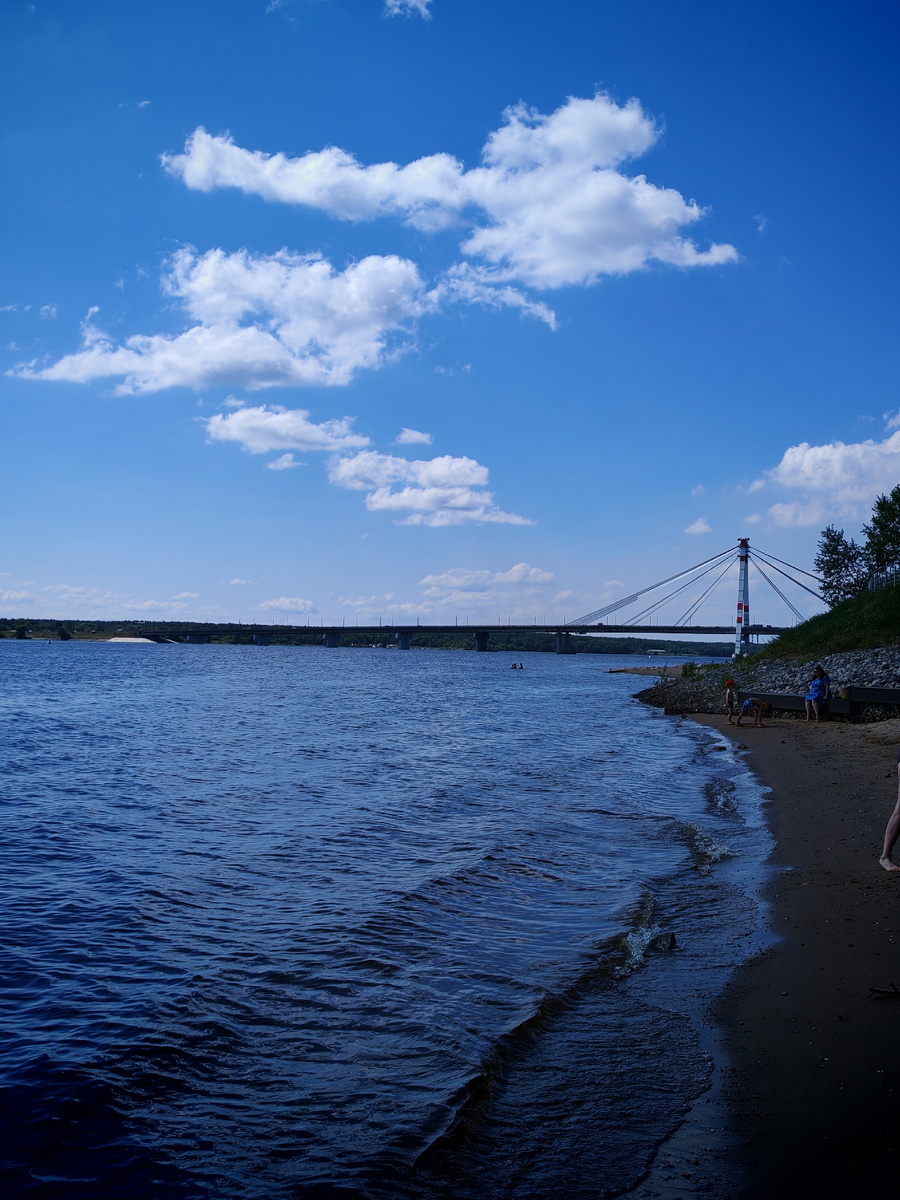 Есть небольшой пляж. Вдалеке виднеется Октябрьский мост.