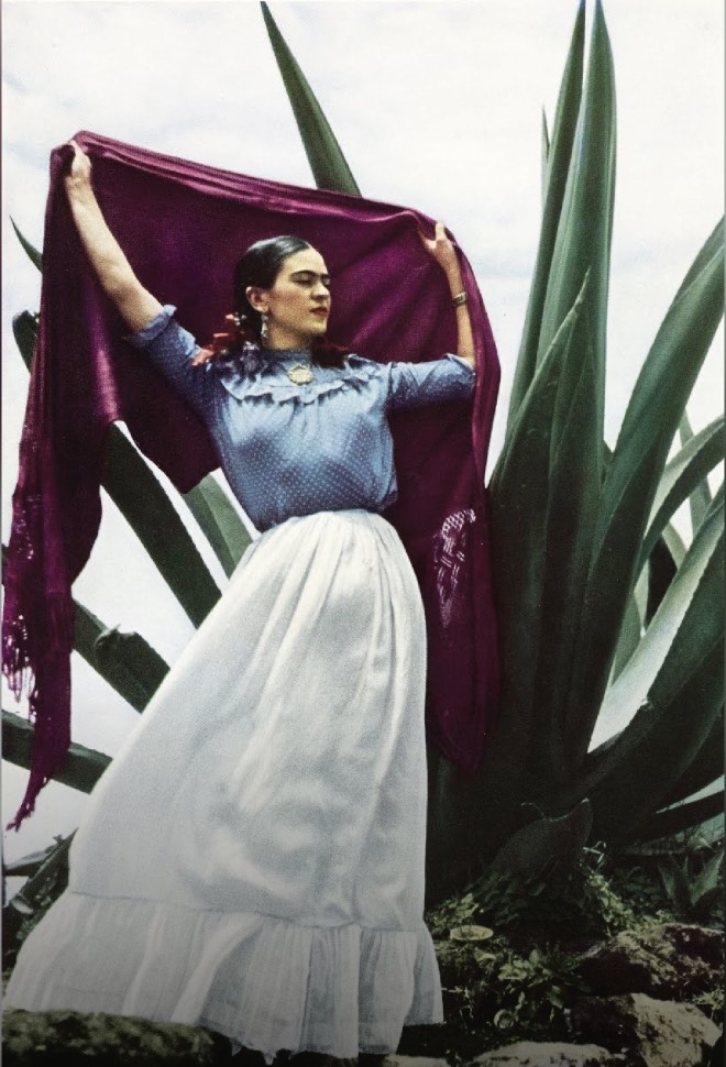 Фотография для Vogue. Блузка в горошек с оборками на кокетке, длинная юбка с оборками по подолу и серьги-подвески. Волосы, разделенные пробором посередине, собраны в две косы, а над головой красивый пурпурный шарф с бахромой.