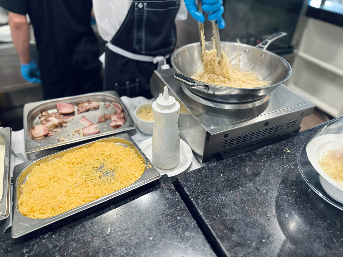 Открытая кухня. В кадре - процесс приготовления пасты Карбонара. За кадром - очередь.