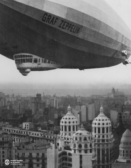 На первом снимке дирижабль парит над центральной частью города, виден силуэт куполов и хорвоздущих зданий
