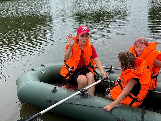 Лёдова Валентина Николаевна машет рукой, сидя в лодке