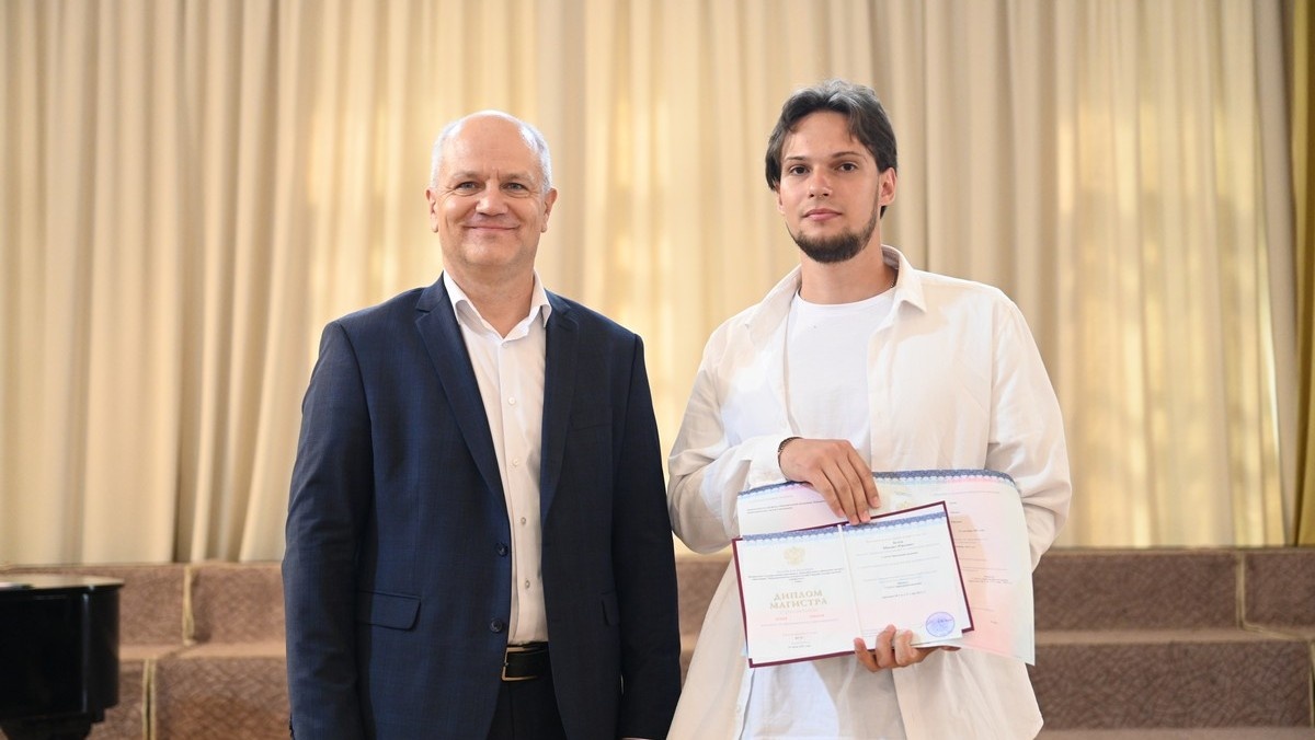 Проректор ТГУ по образовательной деятельности Евгений Луков вручает диплом магистранту ФТФ ТГУ Михаилу Белову