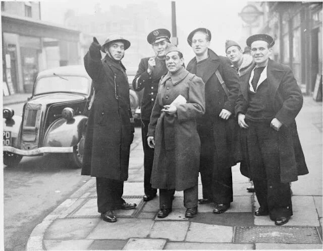 Лондонский полицейский показывает дорогу группе французских моряков и солдат.Переобмундировать в британскую форму их еще не успели. Франция пала совсем недавно. Появилась Сражающаяся Франция генерала де Голя.