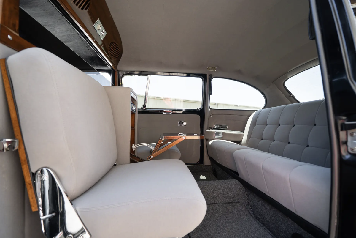 Внутри царит атмосфера гостиной: серые сиденья, откидные сиденья,  красное дерево, раскладной мини-бар и перегородка с электрозатемнением. 