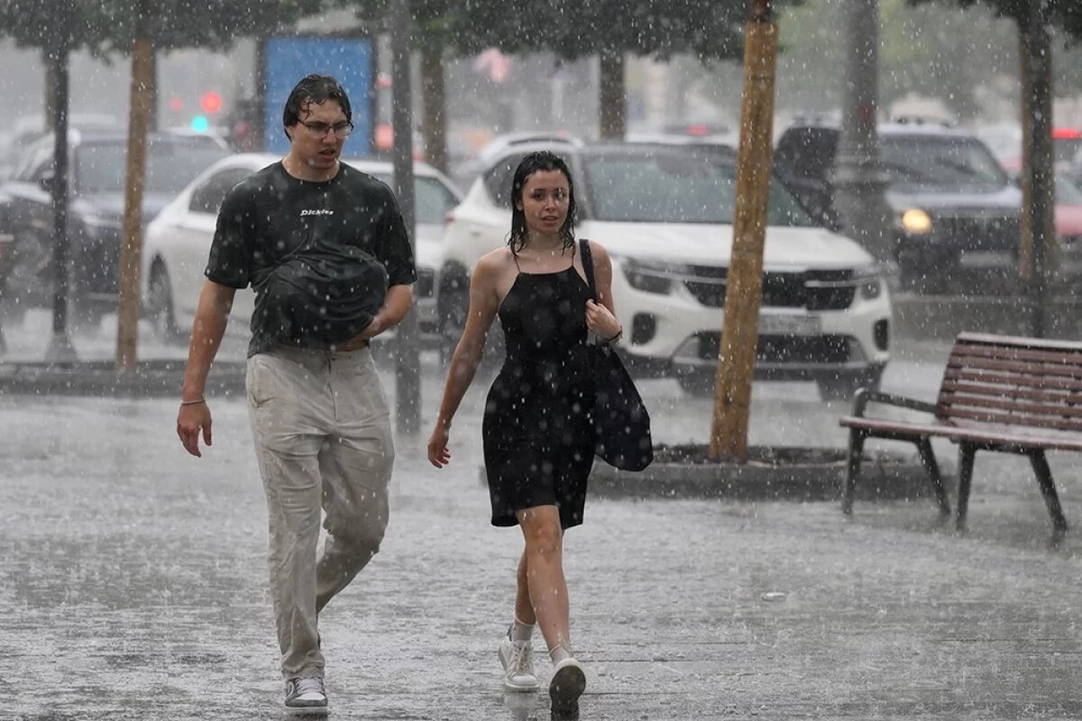    Прохожие идут по Зубовскому бульвару во время ливня в Москве.