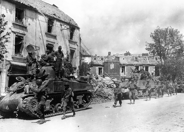Американские бронетанковые и пехотные войска проходят через разрушенный город Кутанс, Франция, в ходе нового наступления на нацистов. Июль 1944 года. Фотография Корпуса связи ETO-HQ-44-9257