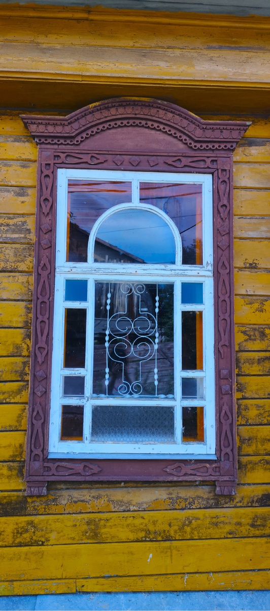 Интеерсное окно с цветными стеклами и маленькой изящной решеткой на улице Горная Слобода в Плёсе