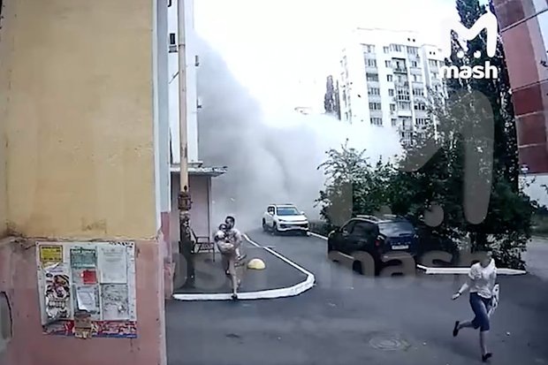    Люди бегут под летящими обломками дома в момент взрыва.. Кадр: Telegram-канал Mash