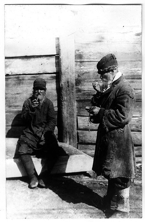 «Челдоны». Парный фотопортрет красноярских крестьян, снятых на фоне бревенчатой постройки. Из собрания Красноярского краевого краеведческого музея