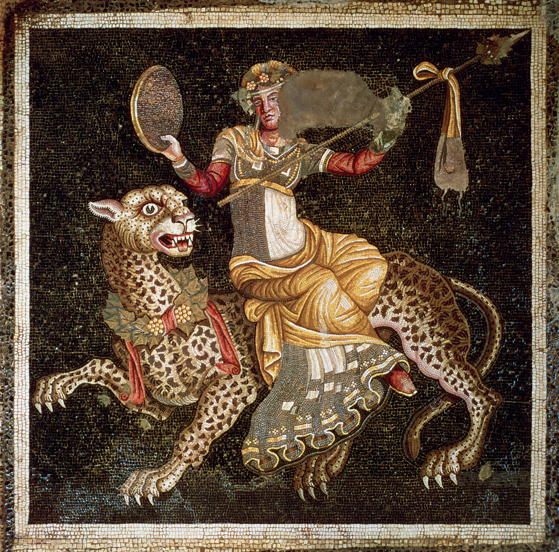 Дионис верхом на пантере
Бог виноградников, вина и всех связанных с ними излишеств, Дионис, обычно ассоциируется с красным цветом, что видно на данной мозаике из Делоса. Однако на этом изображении он не в привычном красном плаще, а облачен в длинное триколорное одеяние, придающее ему более женственный вид, особенно учитывая, что он без бороды. Тем не менее, его атрибуты позволяют без труда узнать его личности. Во-первых, на пантере (или леопарде), на которой он часто изображается; во-вторых, в его руках находятся бубен и тирс, которые также связаны с его образом.
c. 180 - 170 до н. Делос, Греция, Дом масок.