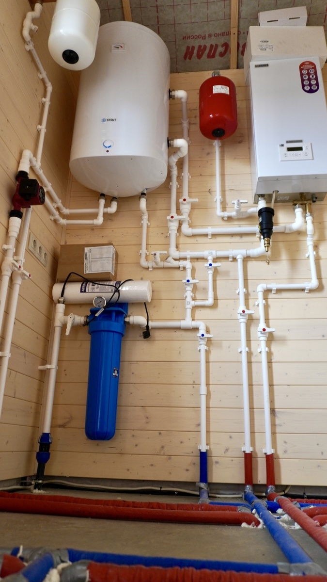 Узел отопления и водоснабжения: бойлер, котёл, фильтрация и разводка по дому. Вся система аккуратно собрана в одном техническом помещении. Фото с объекта «Интел Групп».