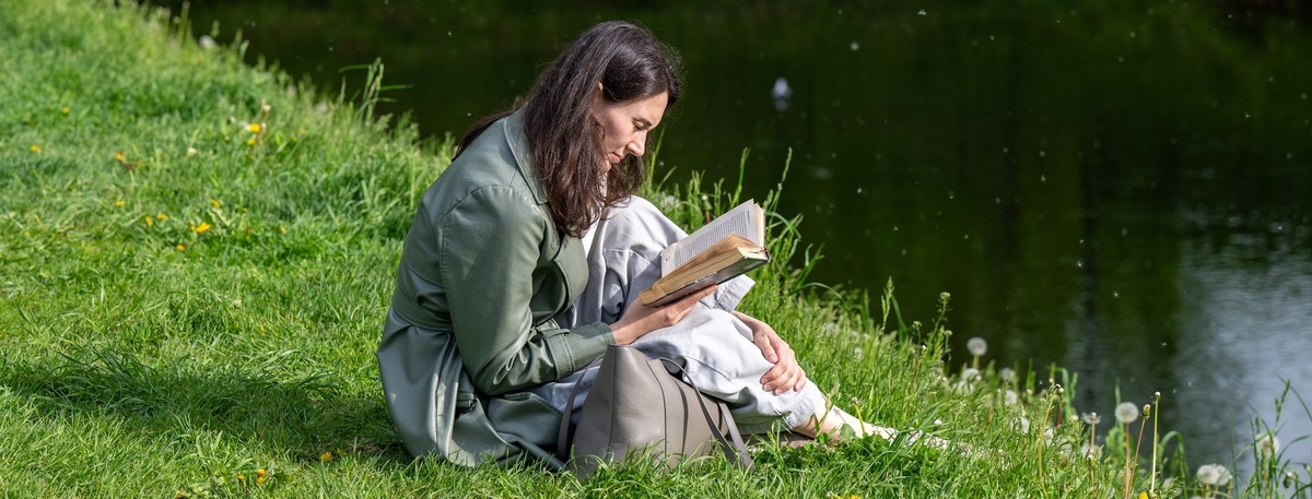    Петербурженка читает книгу, сидя на берегу реки. Автор фото: Михаил Тихонов / "Деловой Петербург"