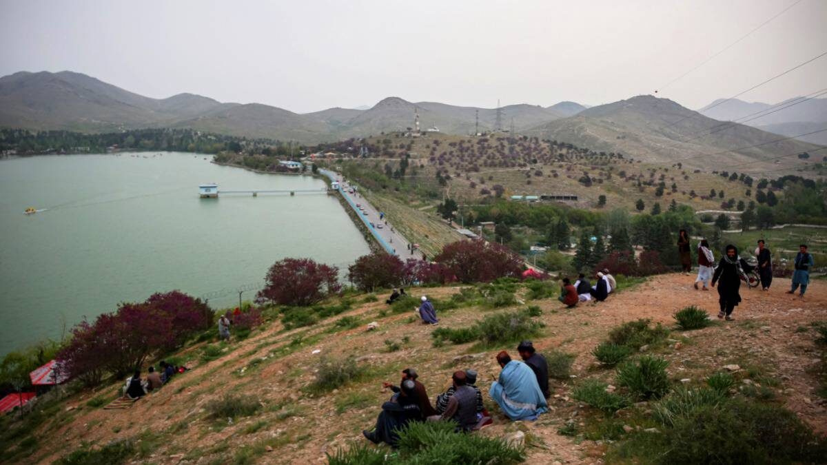    Местные жители наблюдают за отдыхающими на катере туристами на озере Карга на окраине Кабула в Афганистане / Фото: EPA / Samiullah Popal / ТАСС