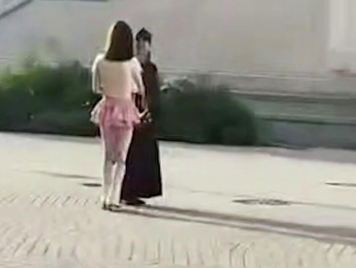    Мужчина в женской одежде разговаривает со священнослужителем на территории Сретенского монастыря. Кадр видео© Соцсети