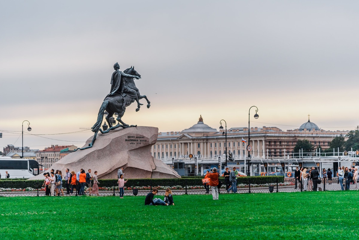 Медный всадник на фоне хмурого петербургского неба, вид сбоку, подчеркивающий динамику и движение.