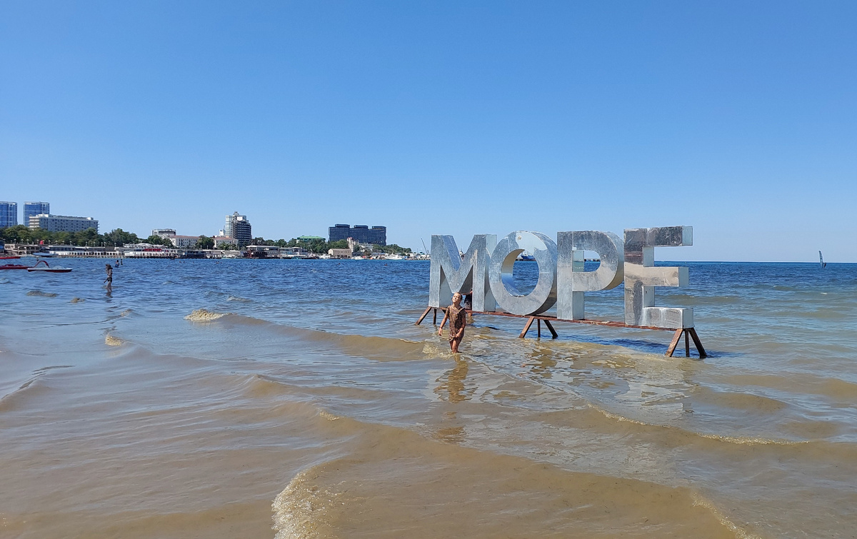 Пляж Анапы в августе 2025 года. Буквы «МОРЕ» — популярная фотозона, где раньше выстраивались очереди. Сейчас море официально закрыто для купания, но туристы всё равно делают снимки на память.