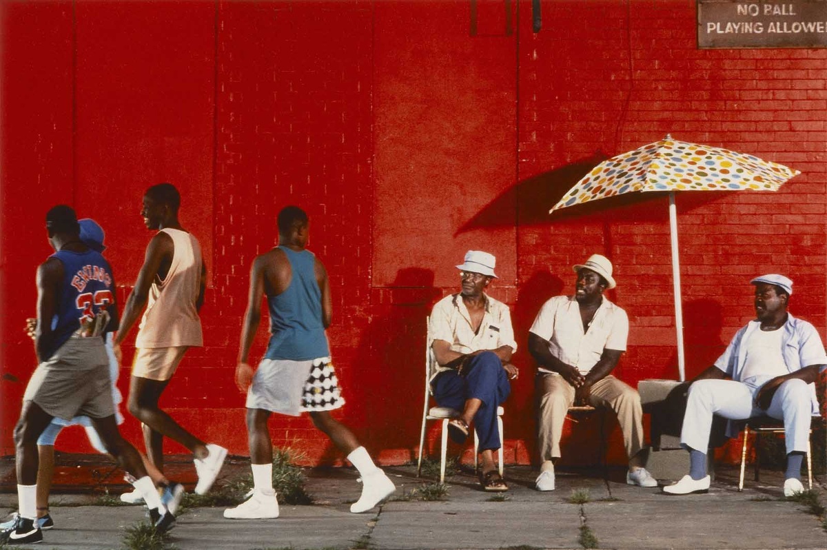 Эти три чувака сидят под зонтом у красной стены при любых обстоятельствах.