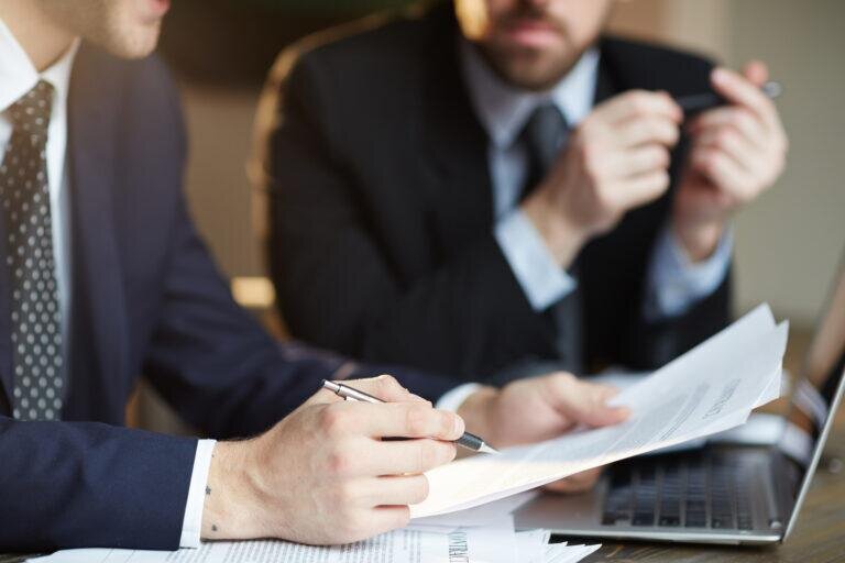   Closeup portrait of two unrecognizable business partners reviewing paperwork and signing contract papers at table during meeting Артем Силантьев