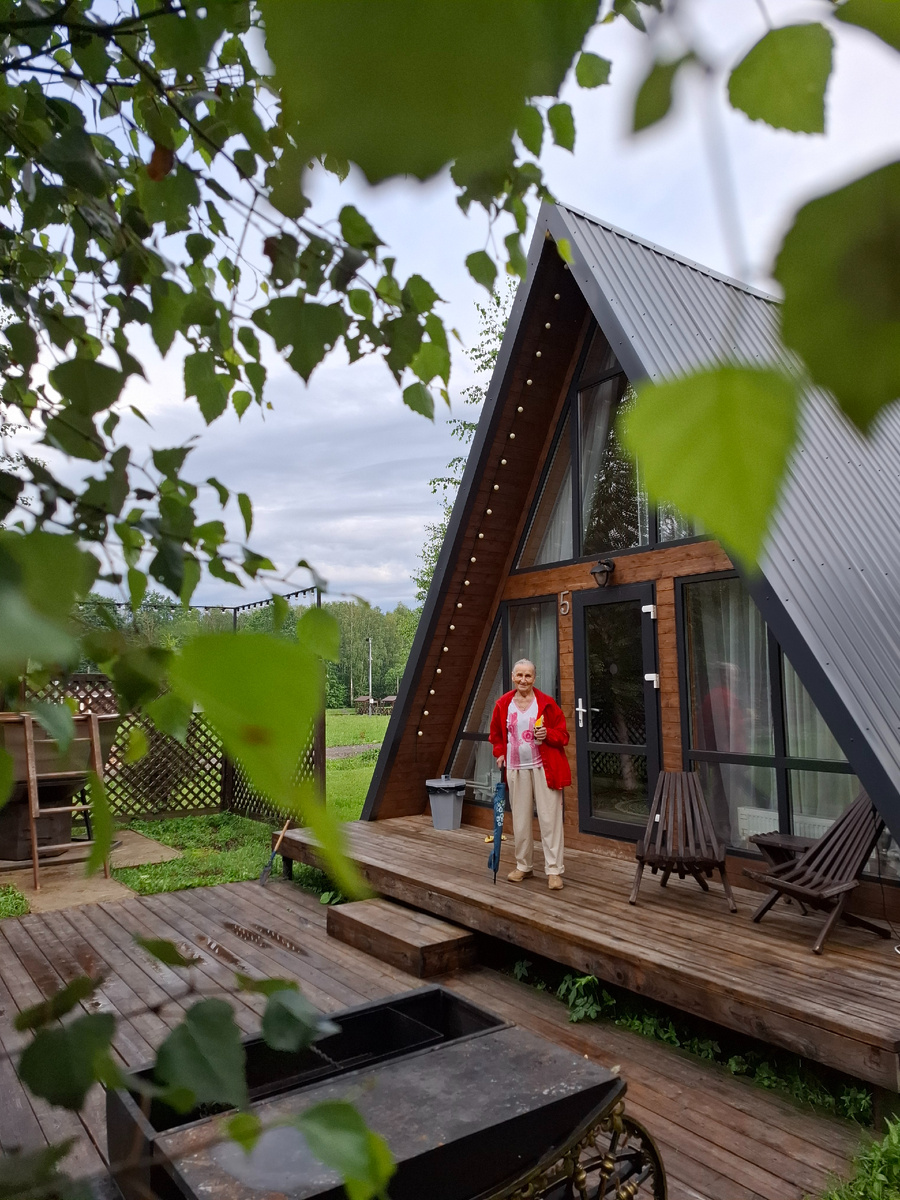 Знакомьтесь, моя мама - Вера Ильинична. Стоит на пороге домика «А-фрейм» в Калужской области. Фото автора.