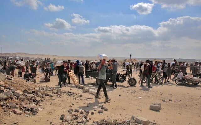 Вынужденные переселенцы-палестинцы несут сумки с гуманитарной помощью, которую они получили в распределительном центре, управляемом Гуманитарным фондом Газы (GHF), поддерживаемым США и Израилем, в центральной части сектора Газа, 4 августа 2025 года. (AFP)