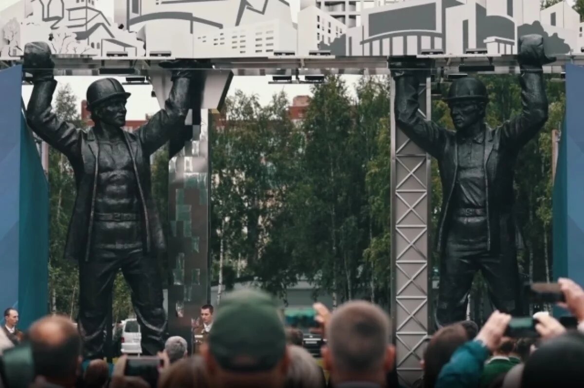    Памятник представляет собой двух строителей, которые держат на руках макет города.