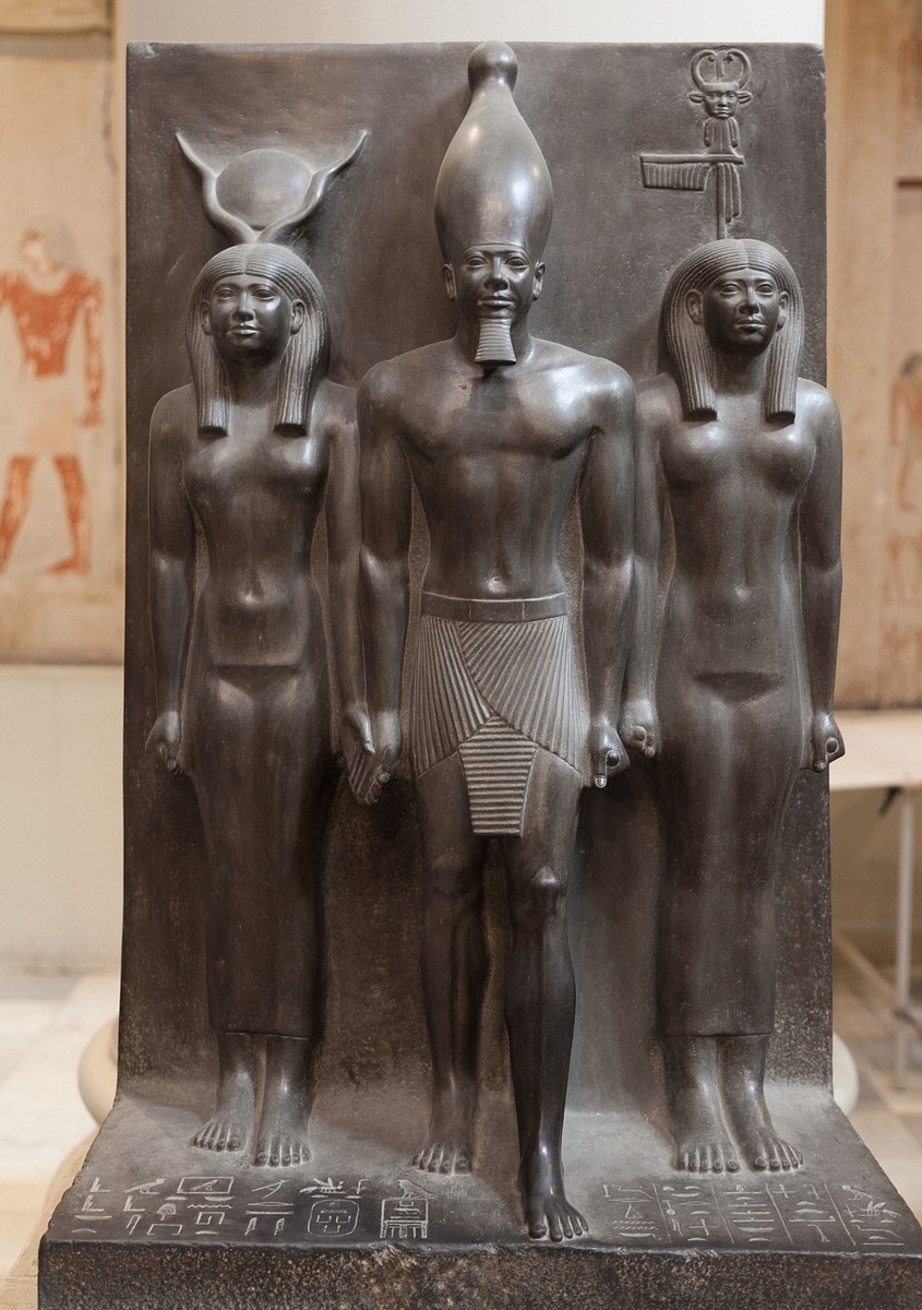 Скульптурная группа, изображающая Менкаура в сопровождении богини Хатхор (слева) и богини-покровительницы VII нома Верхнего Египта Хут-Сехем. Египетский музей, Каир.